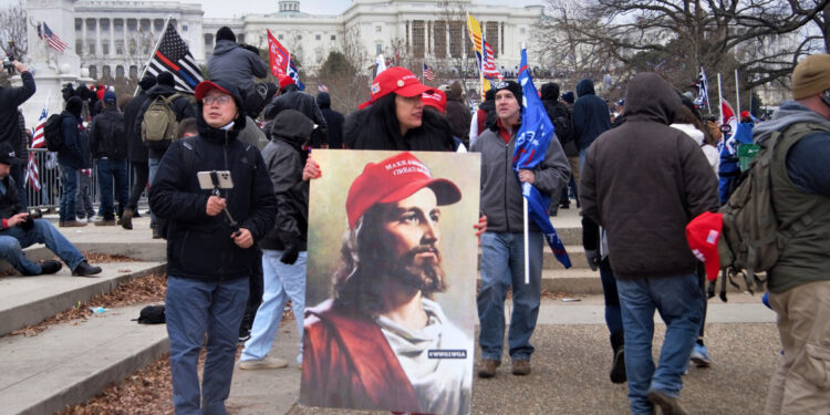 Trump supporter holds a MAGA Jesus poster during the January 6 insurrection. (Photo credit: Tyler Merbler)