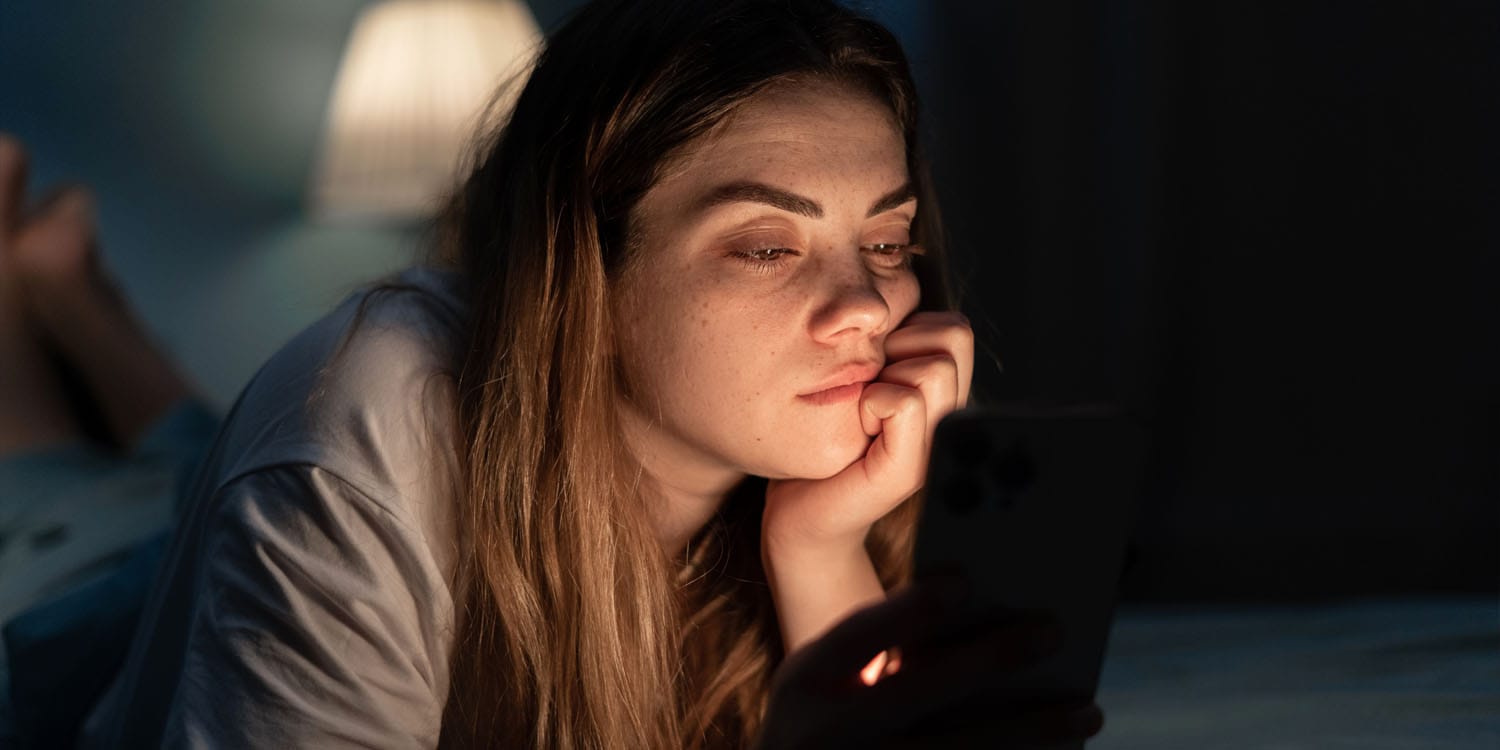 Lonely woman on her smartphone at night