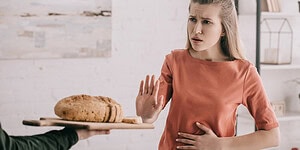 Stunned woman refusing bread at the table, rejecting food in a grocery store or restaurant setting.