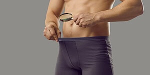 Magnifying glass examining male underwear to symbolize psychological analysis and health research.