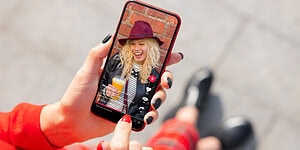 Girl taking a selfie on her smartphone, enjoying a drink, smiling and outdoors, illustrating social media, happiness, and modern communication.